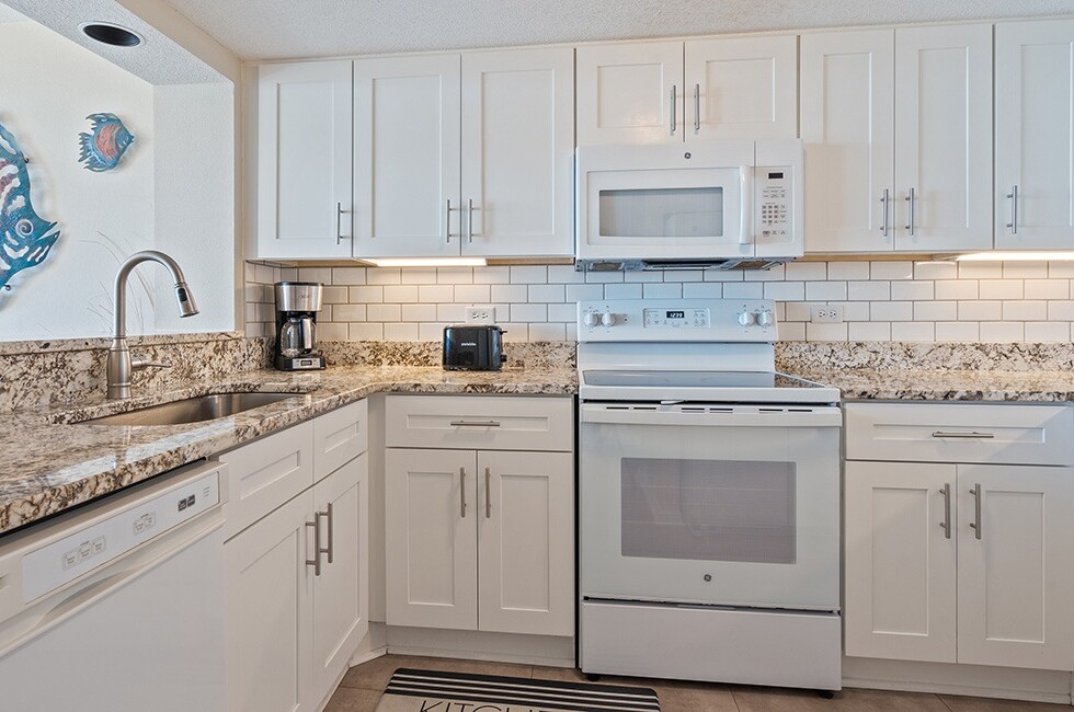 A kitchen with white cabinets, granite countertops, and appliances.