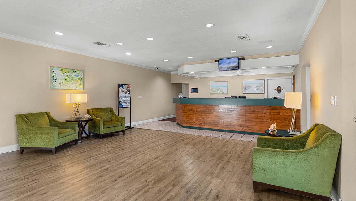 A hotel lobby with a reception desk, seating area, and artwork on the walls.