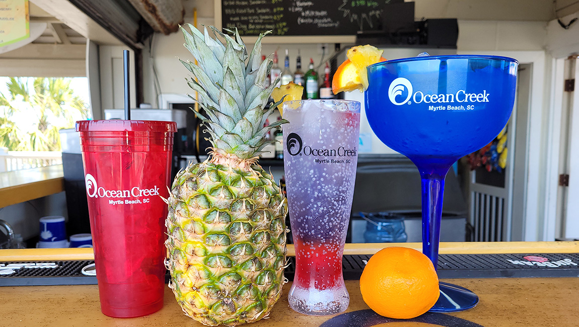 A selection of branded glasses and a pineapple on a bar counter.