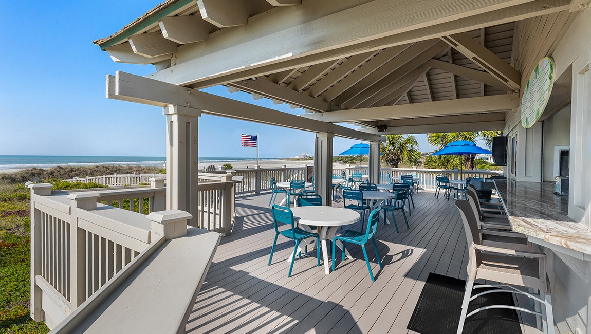 A beachside bar with outdoor seating and a view of the ocean.