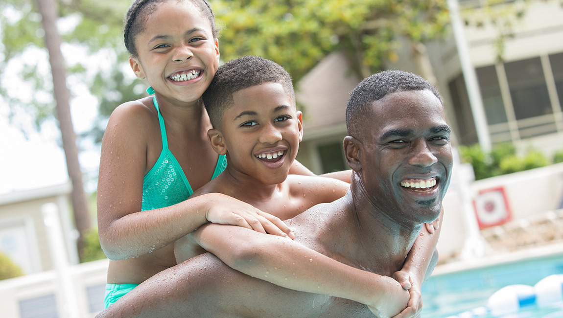 A family of three smiling and having fun in the pool