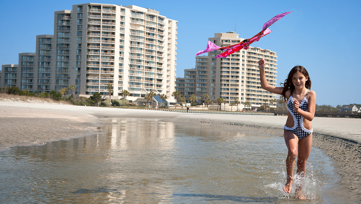 girl flying a kite on the beach